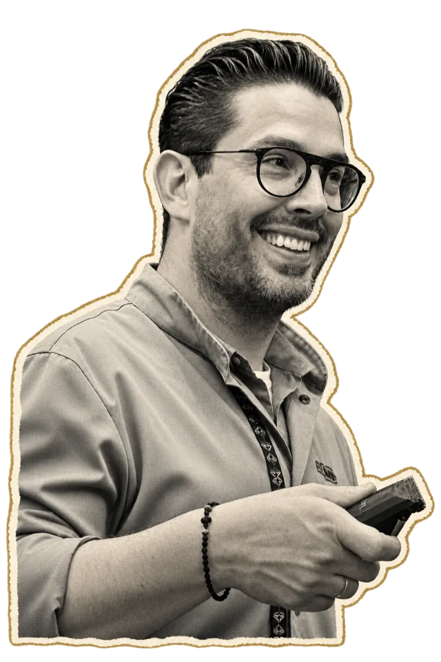 Vasilis, smiling, wearing glasses and holding clippers